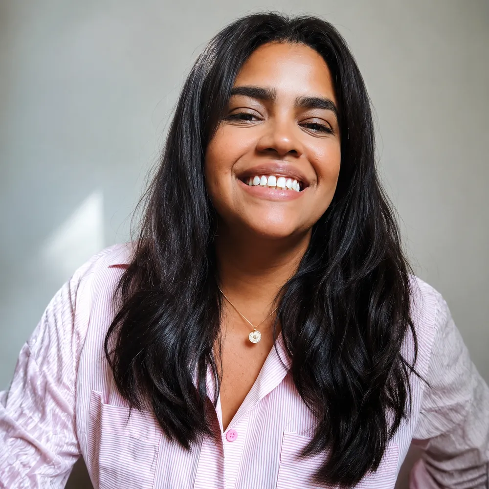 Retrato de Gabriela Peres sorrindo, de camisa listrada rosa