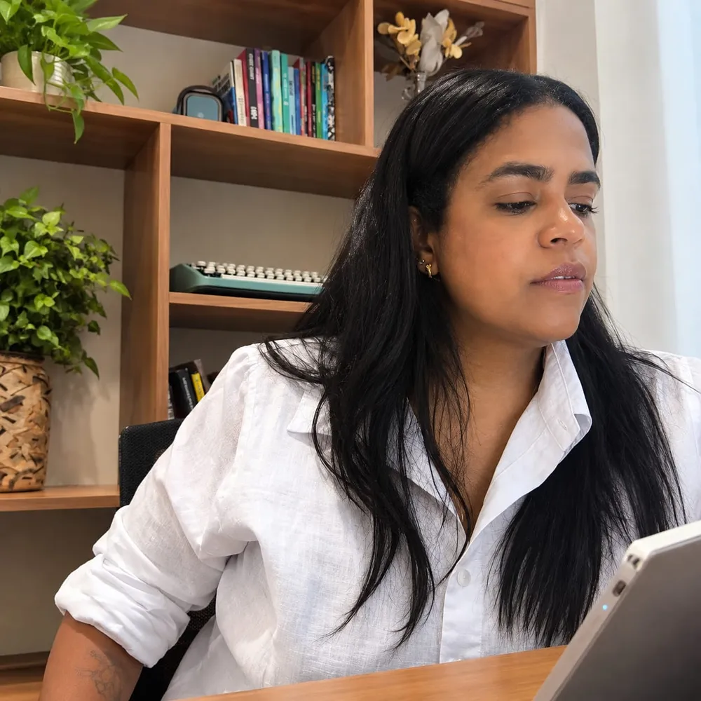 Gabriela Peres analisando um projeto no tablet, de camisa branca